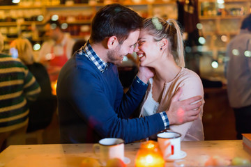 Happy couple kissing at bar and having date