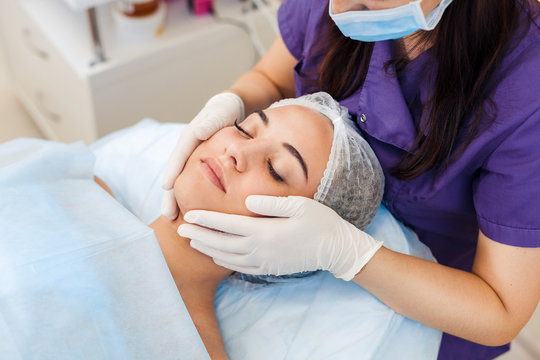 Cosmetologist in gloves mask Applying cream to the face and massages woman. Cosmetic procedures Mechanical cleaning of the face. Cosmetology.