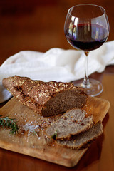 bread and a glass of wine on a wooden board and table
