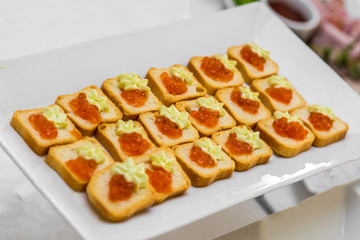 Bread with caviar on a white plate of the banquet table