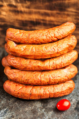 Stack of deliciously smoked handmade Swedish Isterband sausages with natural casing. Here with a tomato.