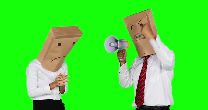Angry anonymous businessman with paper bag on his head, scolding his anonymous worker while yelling with a megaphone. Shot in 4k resolution with green screen background