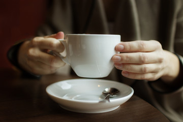 Female hands holding a white cup