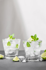Mojito cocktail with lime and mint in glass on a grey stone background