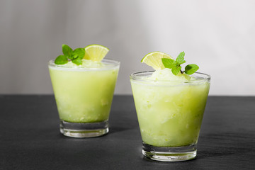 Cocktail juice with lime, mint and ice. Bar drink accessories on black table background.