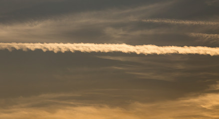 trail from the plane in the sky at sunset