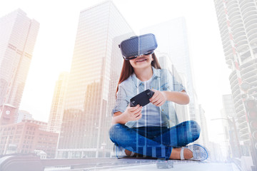 Little girl squatting cross-legged and playing with VR headset