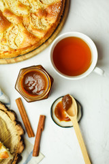 Pie with apple, cinnamon  and jam with cap of tea on a wooden stand. Beautiful sweet cake background