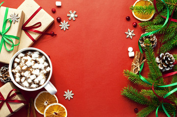 A cup of hot coffee with marshmallow Fir branches Chinks New Year gifts Orange slices Snowflakes Cinnamon. Red Background Copy Space Flat Lay Top View Winter Traditional Drink Food