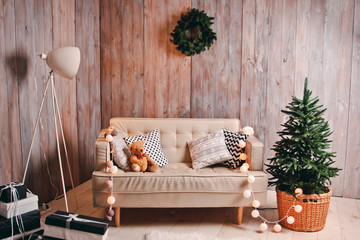 Beautiful festive background with toy Teddy bear sitting with cushions and a garland on the couch