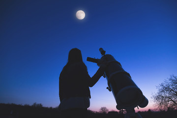 Girl looking at the Moon through a telescope. 