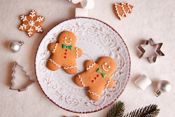 Beautiful Christmas background with gingerbread cookies on a white plate with a branch of a tree and forms for cookies