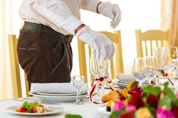 Preparing for a banquet. Waiter places glasses on a banquet table. The feast begins