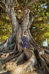 Fototapeta na wymiar ragazza con turbante posa su albero millenario