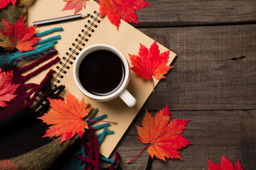 Naklejka na ściany i meble Autumn leaves and a cup of coffee with plaid on old vintage wooden background.