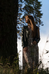 fashion photo of young beautiful woman posing in forest near big tree
