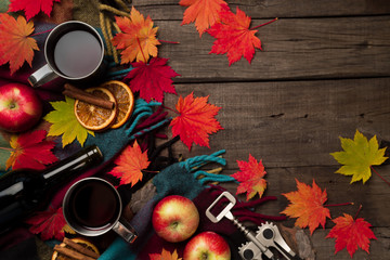 Autumn leaves, two cups of wine, red apples with plaid on old vintage wooden background.