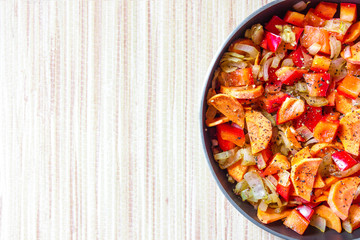 A mixture of red vegetables fried and sprinkled with pepper in the pan. Place for text labels.