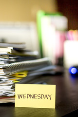 Wednesday; Stack of Documents and Laptop at working Desk.