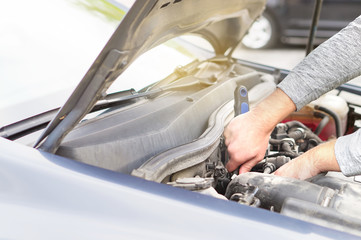 Man fixing engine under the hood. Car repair, maintenance and vehicle inspection concept.  