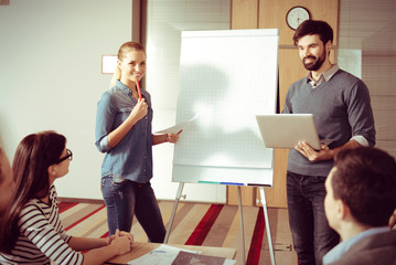Smart young colleagues standing near the flipchart