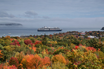 Naklejka premium Cloudy morning in Maine overlooking fall foliage and cruise ship departing.