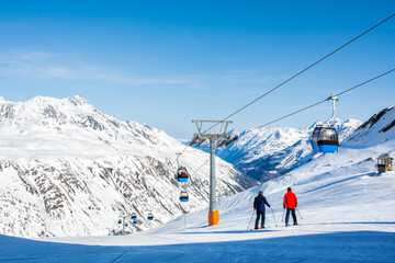 Fototapeta na wymiar Skiers on the background of high snow-capped Alps in sun day, Austria