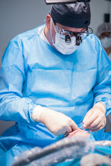 A male dentist in uniform performing dental surgery.