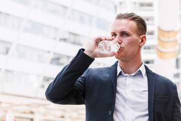 Fototapeta na wymiar Businessman drinking mineral water from bottle