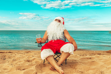 Santa Claus is sitting on the beach.