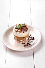 Small cake with different stuffing on a white plate. White wooden table.