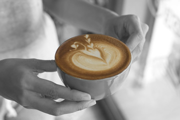 closeup hand holding coffee latte art cup.
