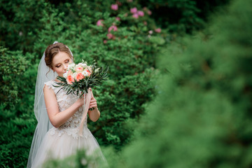 Beautiful blonde bride poses with orange wedding bouquet in the park