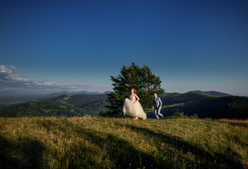 Fototapeta premium Bride runs from groom on the hill