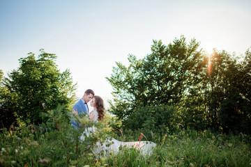 Groom holds bride tender standing before a green tree
