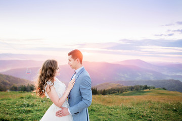 Couple hugs before violet evening sky over the mountains