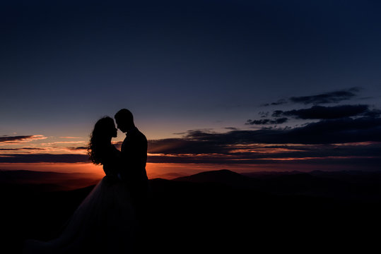 Couple hugs before violet evening sky over the mountains