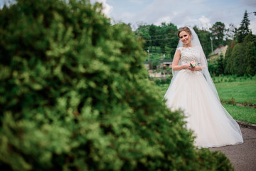 Beautiful bride poses in green park