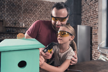 Father helping daughter use drill