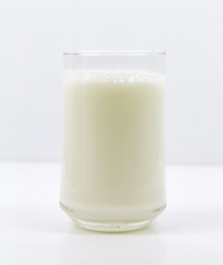 A bottle of milk and glass of milk on a wooden table on a  background