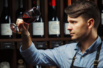 Bokal of red wine on background, male sommelier appreciating drink