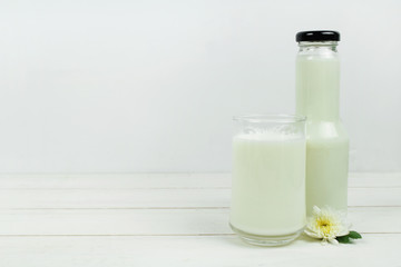 A bottle of milk and glass of milk on a wooden table on a  background