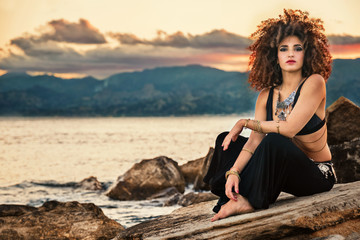 ragazza danza sugli scogli al tramonto in riva al mare