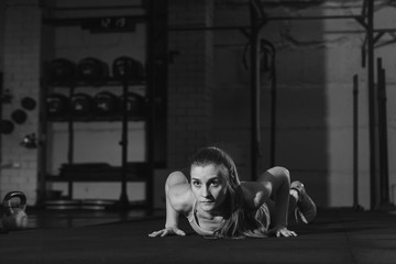 Fit woman in colourful sportswear doing burpees on a exercise mat in a grungy industrial type space