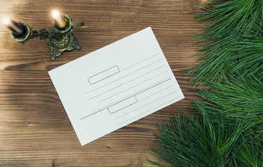 Christmas letter envelope on the table with fir tree branches in the light of burning candles. Christmas congratulatory letter.