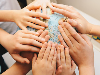 Kids hands together on globe - diversity education concept
