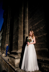 Bride and groom stand apart before a tall building