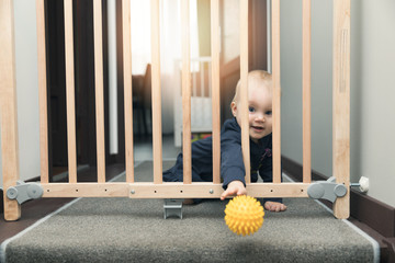 child throwing ball away through safety gates in front of stairs
