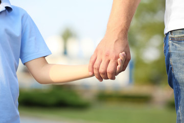 Boy holding father's hand outdoors
