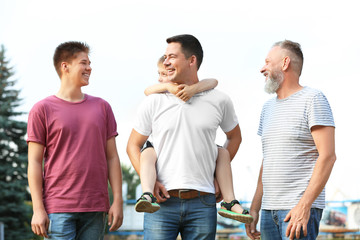 Cute boy with brother, daddy and grandfather outdoors
